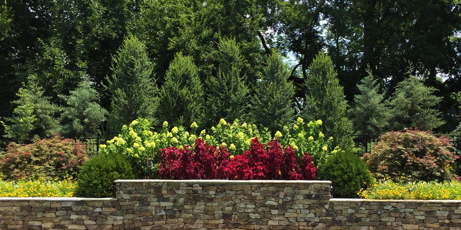 Luxury Landscape Design Services in Nashville TN. Hardscape wall with seasonally enhanced garden.